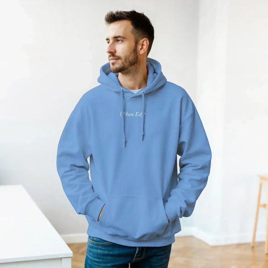 Man wearing classic unisex pullover hoodie in light blue with front pouch pocket and adjustable drawstring hood indoors